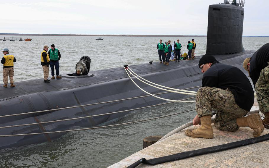 Sailors adjust mooring lines of a submarine