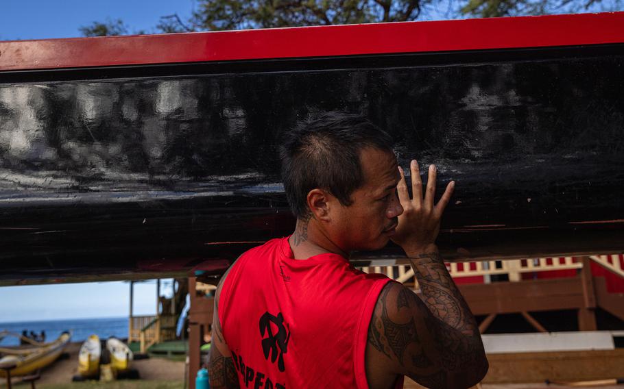 Teddy Ah Puck and members of the Lahaina Canoe Club carry a canoe as they prepare to paddle out from Hanakaoʻo Beach to honor Carole Hartley. 