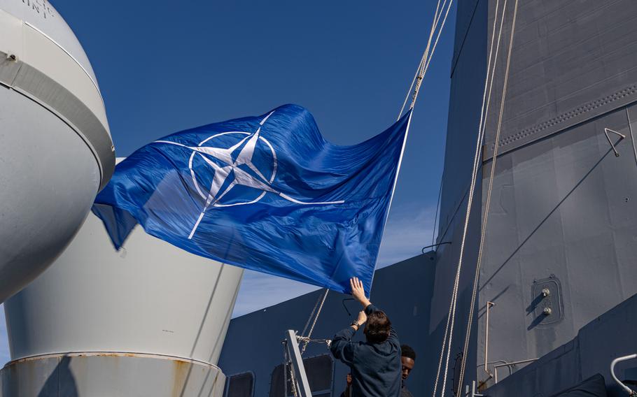 A NATO flag is raised aboard the USS Mesa Verde