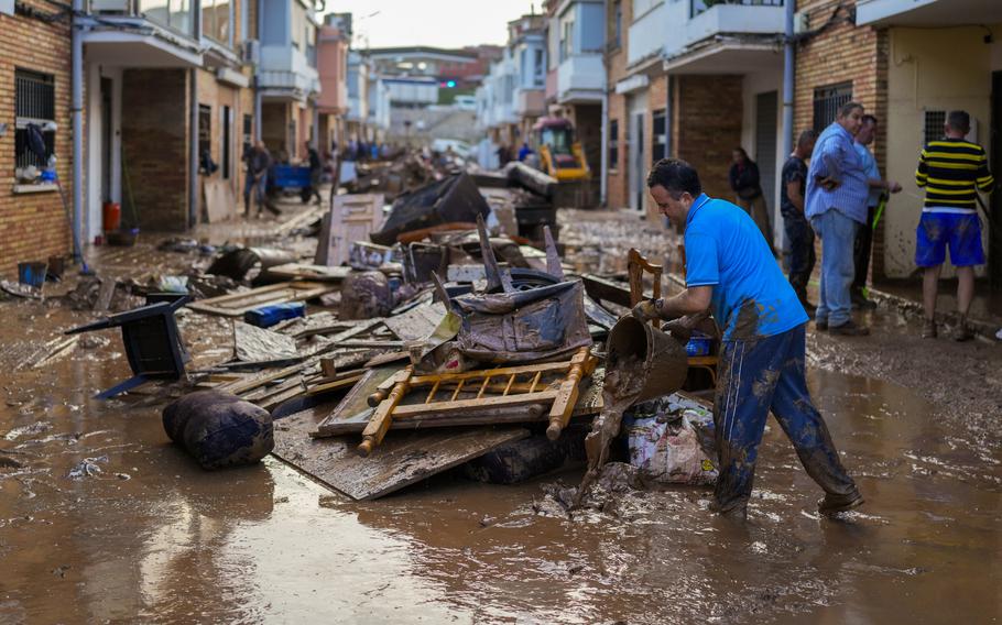 A man cleans up debris outside his house after a flood in Valencia, Spain.