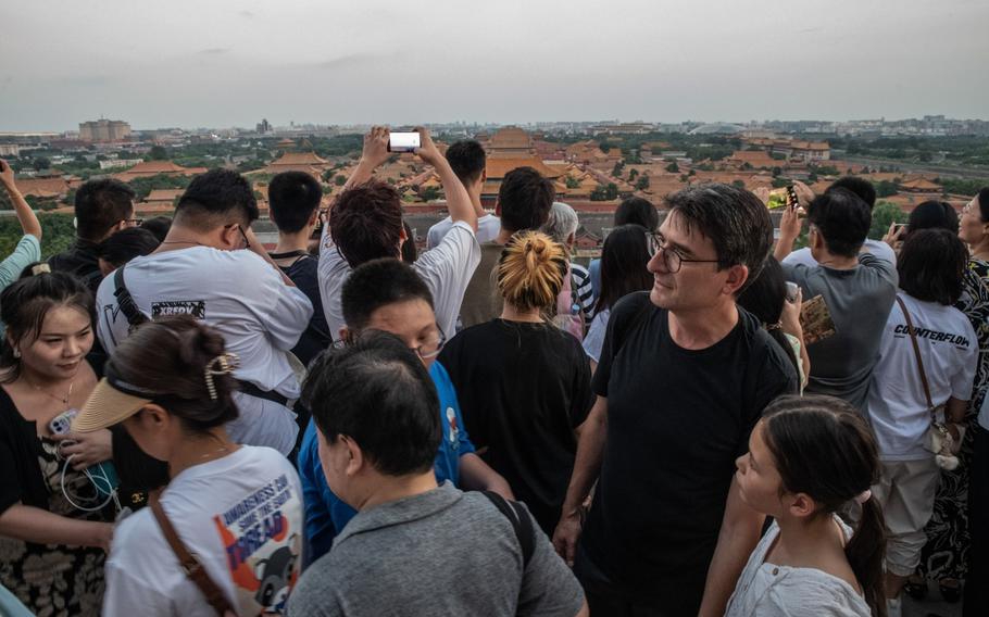 A French tourist stands among a crowd of Chinese tourists gathered to see the Forbidden City at sunset in Beijing on Aug. 12, 2023.