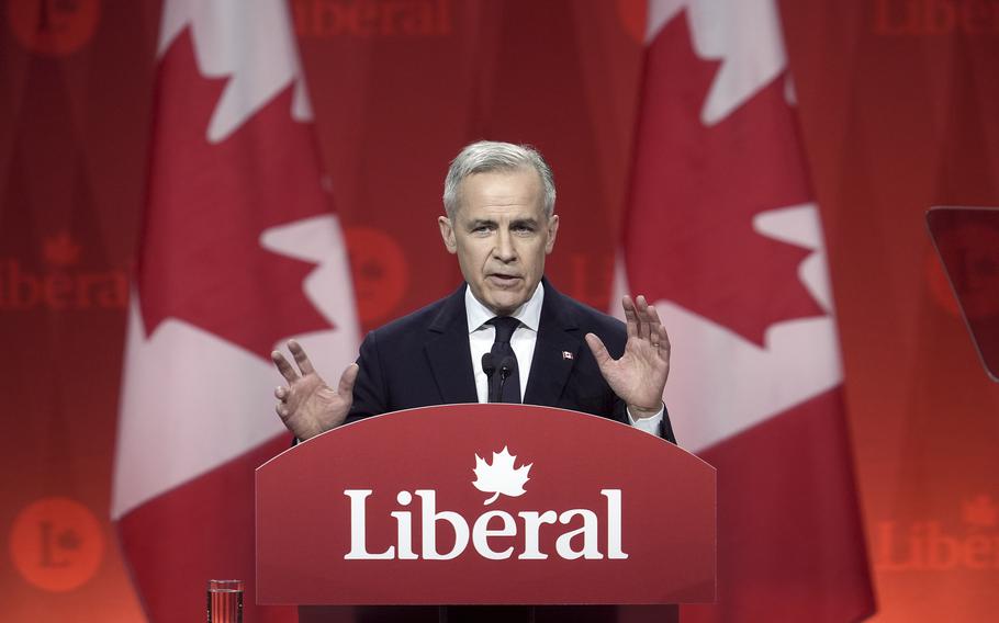 Liberal Party of Canada Leader Mark Carney speaks in front of two Canadian flags.