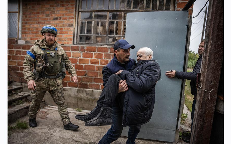 A man helps his elderly father, who is unable to walk, out of his house as Kharkivskyi evacuates civilians from Vovchansk.