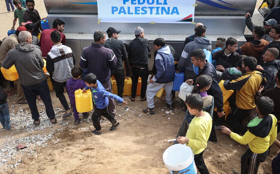 Ibrahim, center, tries to fill a water jug in Rafah in the Gaza Strip on Jan. 21, 2024.. 