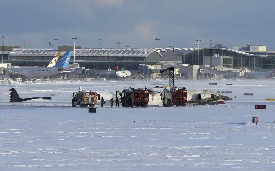 Firefighters work on an upside down Delta Air Lines plane in the snow.