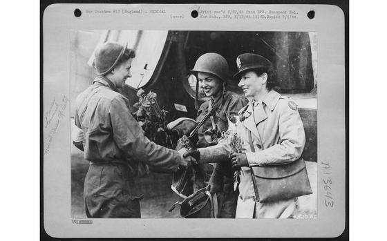 2nd Lt. Suella Bernard smiles and shakes hands with Lt. Foster, head nurse, while 2nd Lt. Mary Jane Brown of Columbus, Ohio, looks on. Nurses Brown and Bernard were two of the five nurses who brought poppies together with wounded from a beach head in Normandy. The five were first to go on this Ninth Air Force Evacuation mission and first to return with wounded to England. 