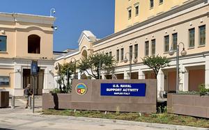 A sign in front of a building reads “U.S. Naval Support Activity Naples, Italy.” 