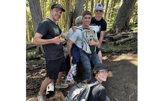 Ursula Bannister on Airman Troy May's back, after she broke her leg hiking near Ashford, Wash. Several people volunteered to help Bannister get down the trail, including Tim Meyer, left, Emily O'Brien, bottom, and Layton Allen, right. (MUST CREDIT: Courtesy of Ursula Bannister)