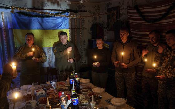 Ukrainian servicemen of 117th Separate Heavy Mechanized Brigade pray before a Christmas dinner on Pokrovsk direction, Donetsk region, Ukraine, Tuesday, Dec. 24, 2024. (AP Photo/Evgeniy Maloletka)