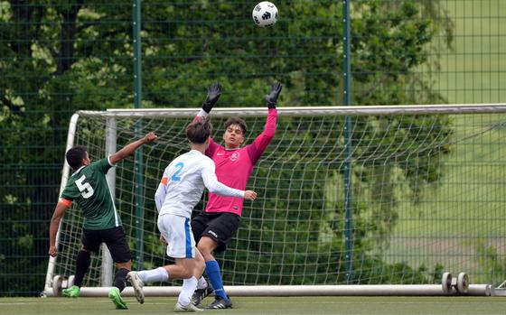 Joaquin Villescas, left, lifts the ball over Marymount keeper Romano Orsini on his way to scoring the 1-0 winning goal in a Division II game at the DODEA-Europe soccer finals at Reichenbach-Steegen, Germany, May 21, 2024. Marymount’s Wayne Pomillio watches.