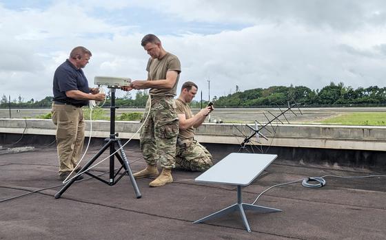 Air Force personnel and a contractor set up communications equipment on a Palau rooftop during the Rally in the Pacific exercise, Sept. 12, 2023.