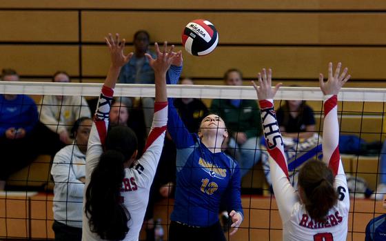 Wiesbaden's Samantha Knieriem slams the ball as Kaiserslautern's Kezley Kai, left, and Rozlynn Onnen jump for the block during a match on Sept. 21, 2024, at Kaiserslautern High School in Kaiserslautern, Germany.