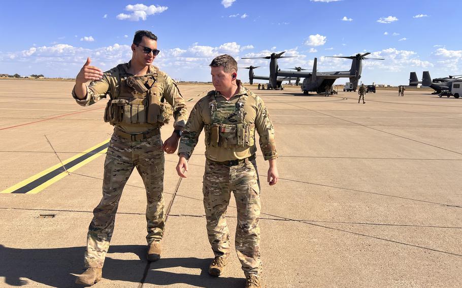 Maj. Lucas Duncavage and  Lt. Col. Seth Buckley walk on the flightline in front of a V-22 Osprey. 