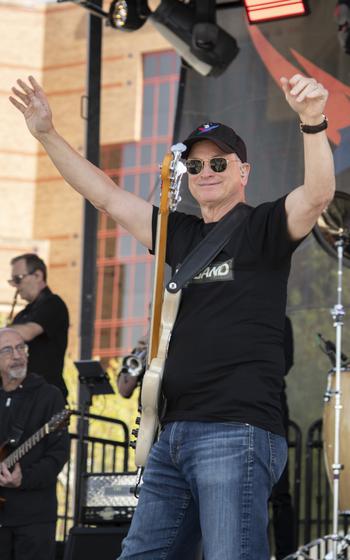 Gary Sinise with his arms in the air on stage