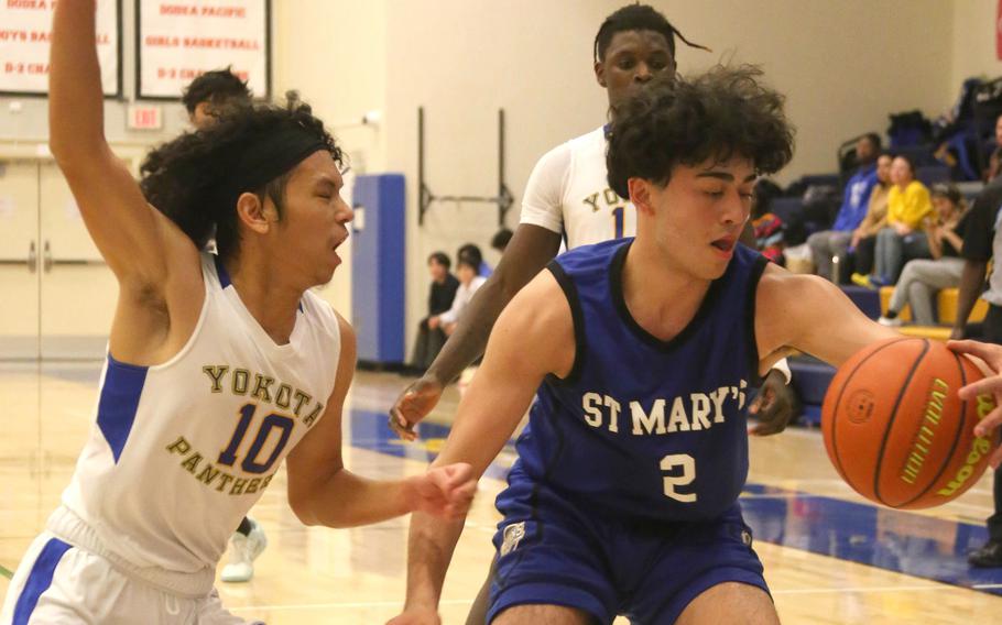 Yokota’s Royce Canta guards St. Mary’s Max Wahba during Thursday’s Kanto Plain boys basketball game. The Titans won 67-63 in a matchup of last year’s Far East Divisions I and II tournament champions.