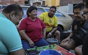 Men and women in Mexico City playing the board game poleana next to a car. 