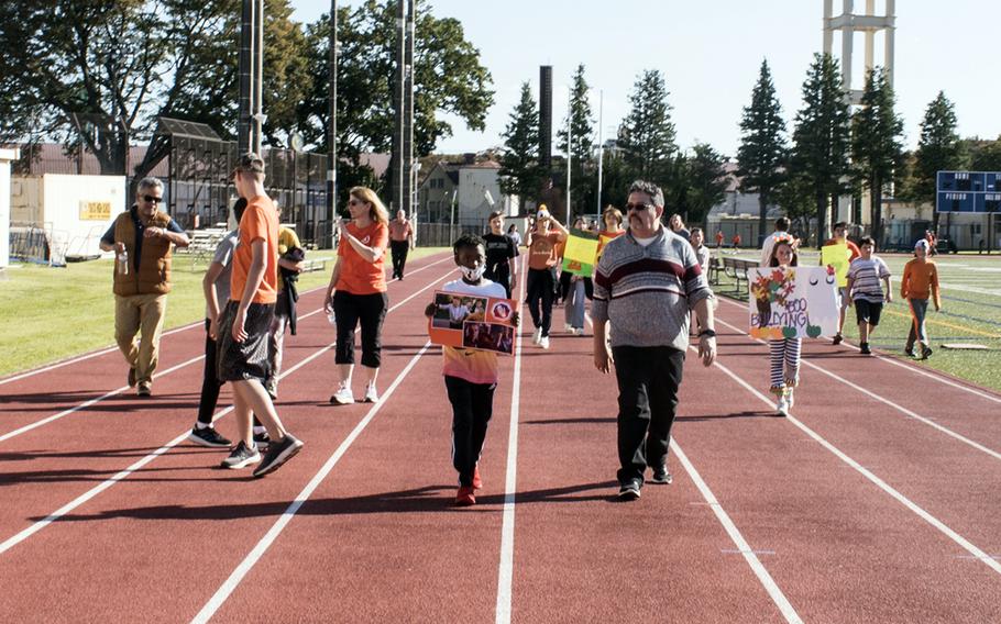 A Yokota Middle School student holds a sign featuring famous big-screen bullies during an anti-bullying walk at Yokota Air Base, Japan, Oct. 26, 2023. 