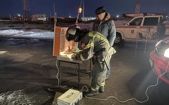 A firefighter bends over a table writing information down on paper.