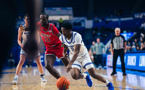 An Air Force Academy player in blue and white runs with the ball while an Aztec player in red guards him.