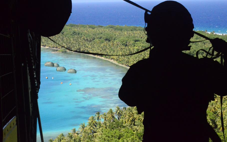 Airman watches Operation Christmas Drop bundles drift to islanders. 