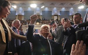 President Trump raising a fist as he leaves a congressional chamber.