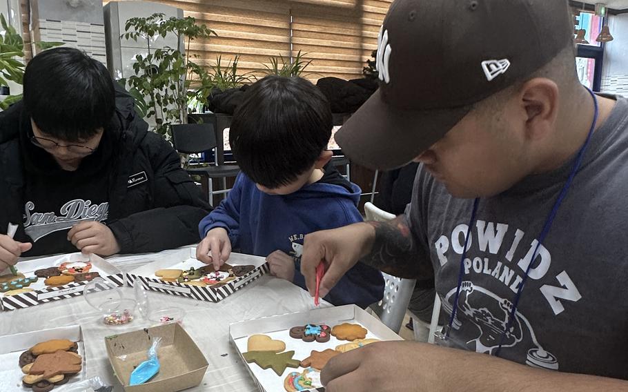 A soldier decorates cookies with a child.