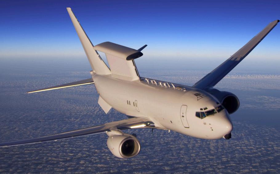 An E-7 Airborne Early Warning and Control Aircraft flies above the clouds with a blue sky in the background.