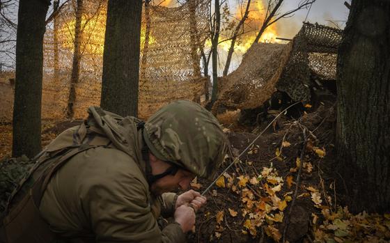 A Ukrainian national guard member crouches behind camouflage.