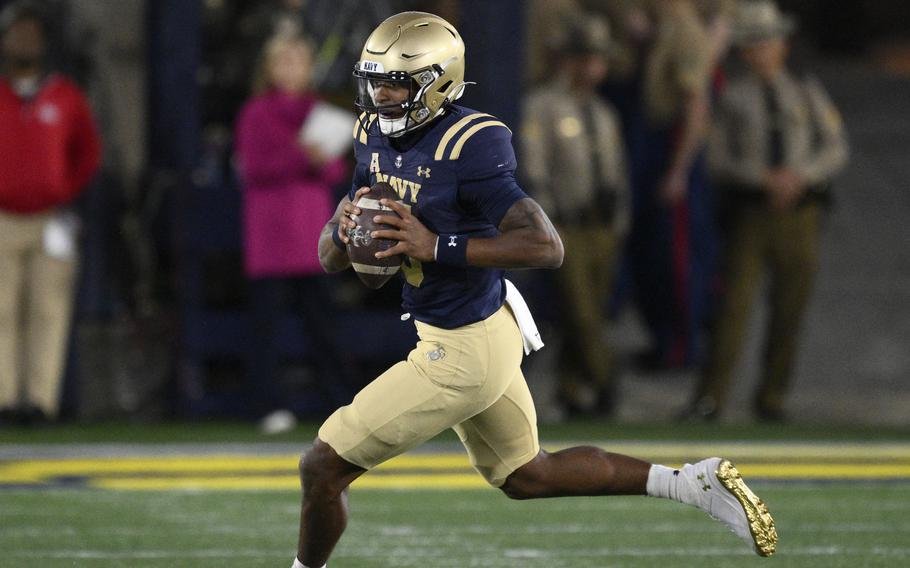 Navy player Braxton Woodson runs with the ball during a college football game.