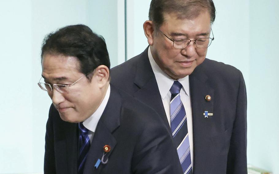 Japan's Prime Minister Fumio Kishida, left, walks past the newly elected head of the Liberal Democratic Party Shigeru Ishiba after the party's leadership election at its headquarters in Tokyo. on Sept. 27, 2024.