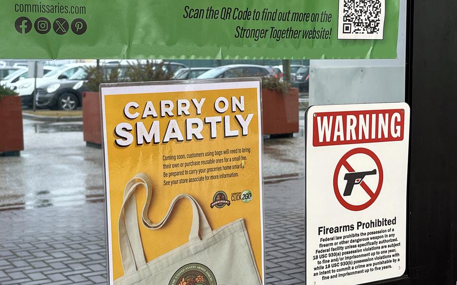 Signs on the window of a commissary tell patrons to Carry on Smartly, meaning plastic bags will be phased out and reusable bags will be phased in.