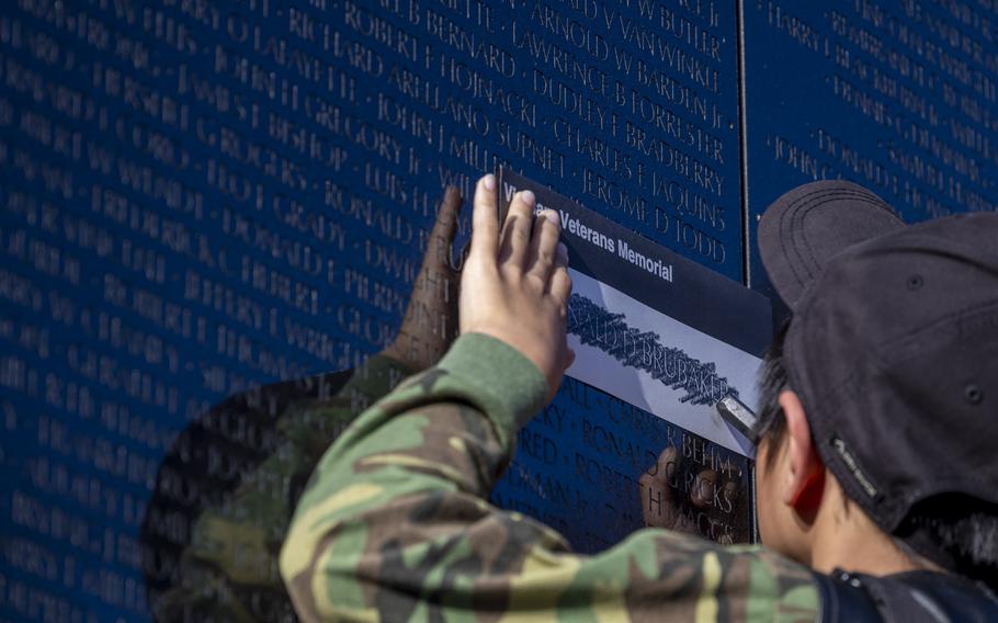 A boy makes a rubbing of a name from the Vietnam memorial.