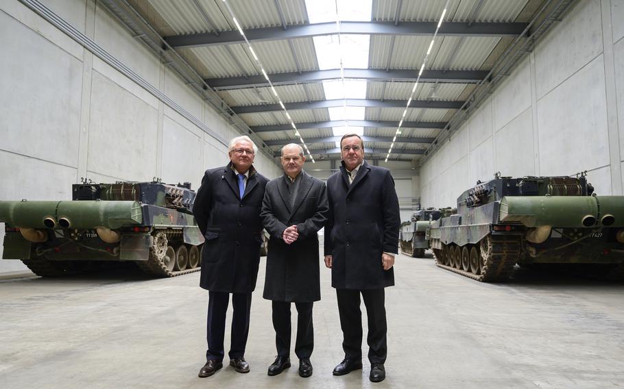 The officials stand in a hall with Leopard 2A4 main battle tanks.