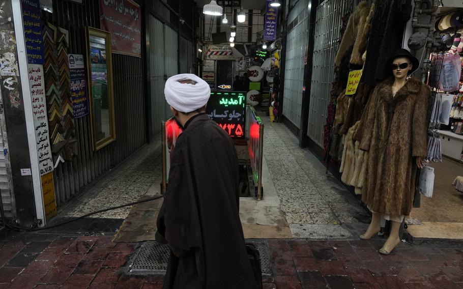 A cleric walks in front of a shopping center in northern Tehran