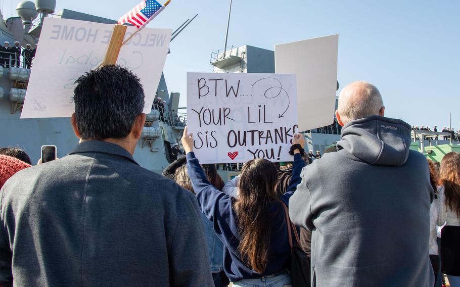 Family and loved ones hold signs during a homecoming ceremony for the USS Stockdale