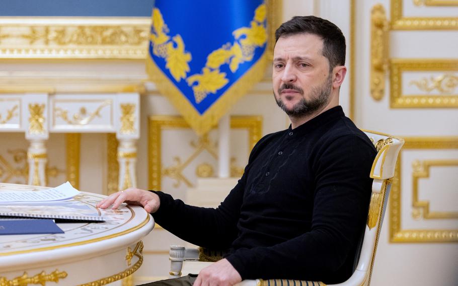 Ukrainian President Volodymyr Zelenskyy seen from the waist up, sitting in a highly-decorated chair and table.