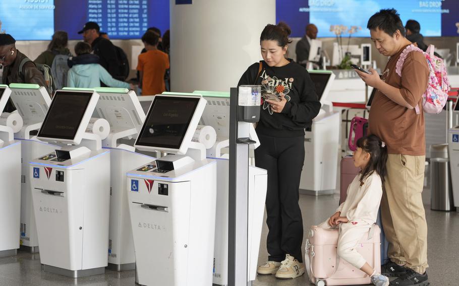 Travelers self-check at Delta Airlines kiosks at Los Angeles International Airport