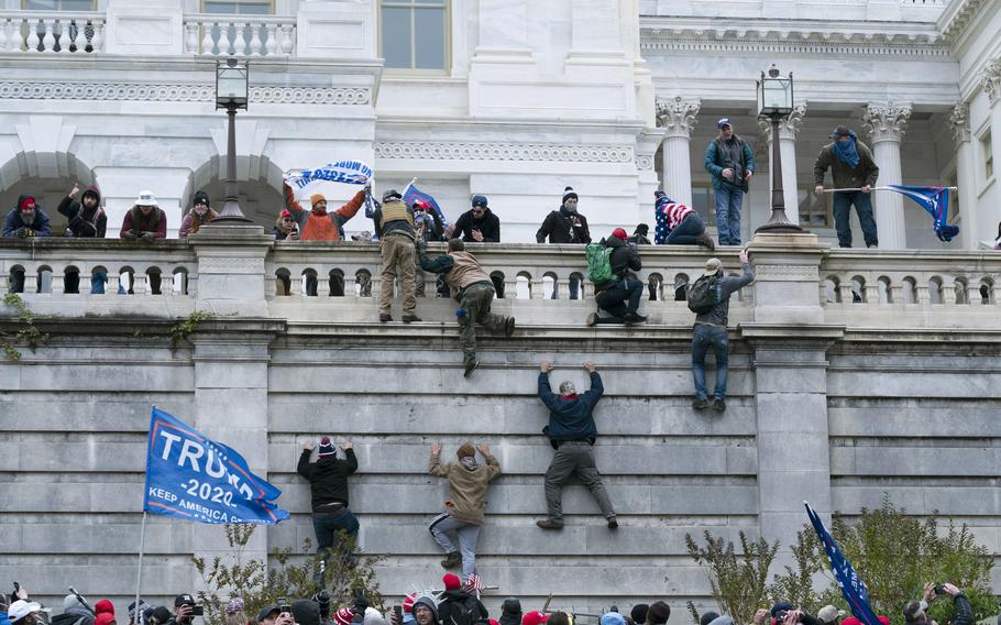 Supporters of President Donald Trump climb the west wall of the the U.S. Capitol.