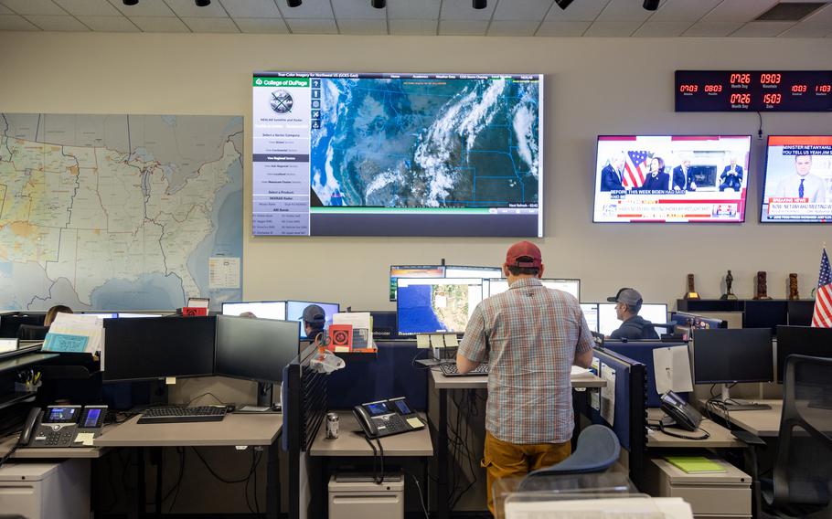 Employees work beneath a giant screen showing current fire conditions at the National Interagency Coordination Center in Boise. 