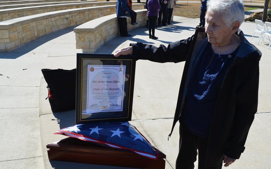 A woman stands and looks at an award and a folded American flag.