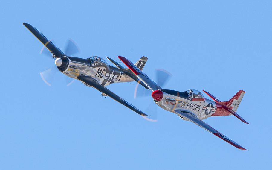 The propellers are blur as two P-51s take flight.