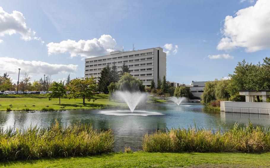 A hospital building with a large pond in the foreground.