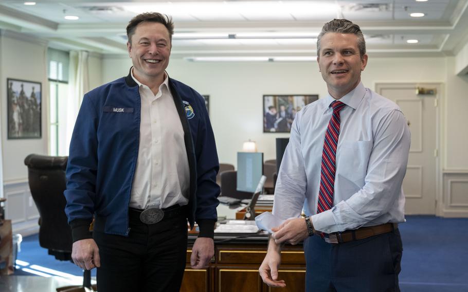 Musk and Hegseth standing next to each other in front of a desk.