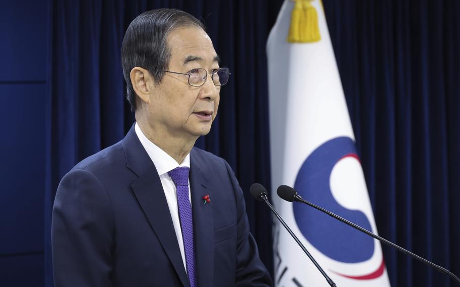 South Korean acting President Han Duck-soo is shown speaking into two microphones. 