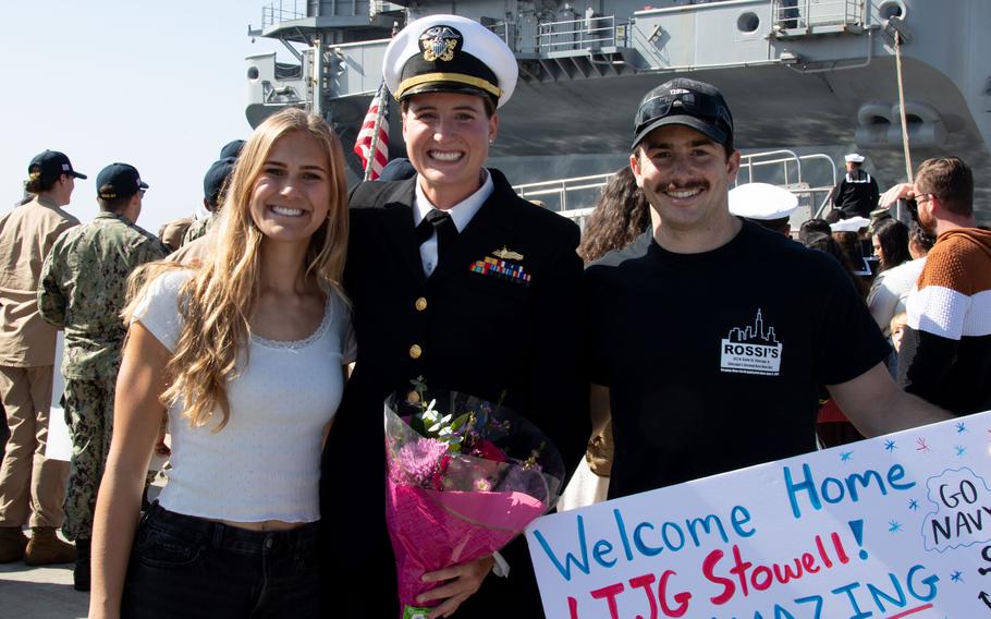 A sailor poses with loved ones for a photo