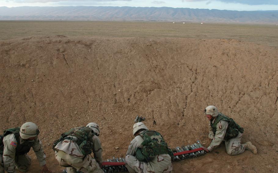 Combat engineers with Company C, 326th Engineering Battalion, attached to the 101st Airborne Division, prepare to detonate grenades and mortars in a mountainous area near Sinjar, Iraq. The weapons were turned in by nearby villagers. 