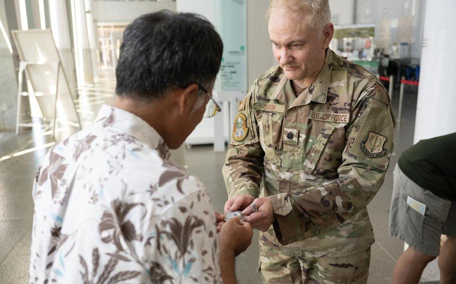 Lt. Col. Patrick Cichon, commander of the California Air National Guard’s 129th Medical Group, presents a challenge coin at the Okinawa Prefectural Peace Memorial Museum on July 20, 2024.