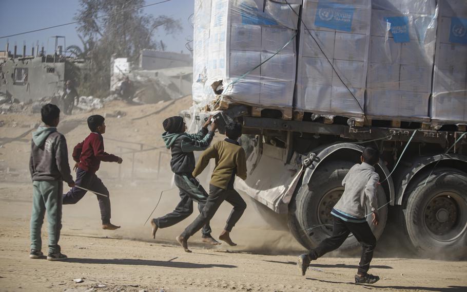 Boys chase a humanitarian aid truck.