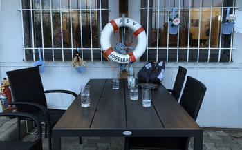 An outdoor dining table in front of a small white building