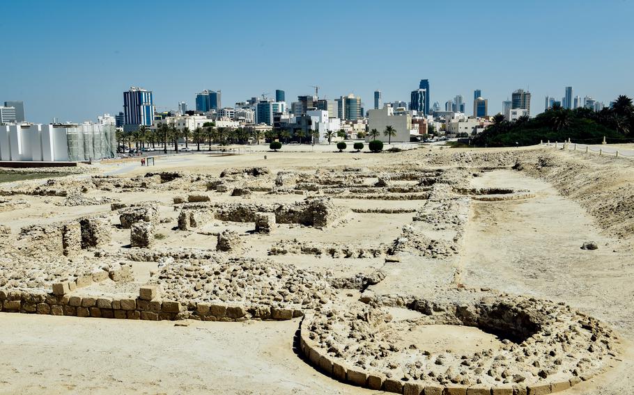 Remains of walls can be seen on the ground at the Bahrain Fort with downtown Manama visible in the background. The Fort was designated a UNESCO World Heritage Site in 2005.